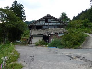 主滑落崖西部に位置する家屋の被害.家屋の奥の崖は滑落崖部分(変位約2m)