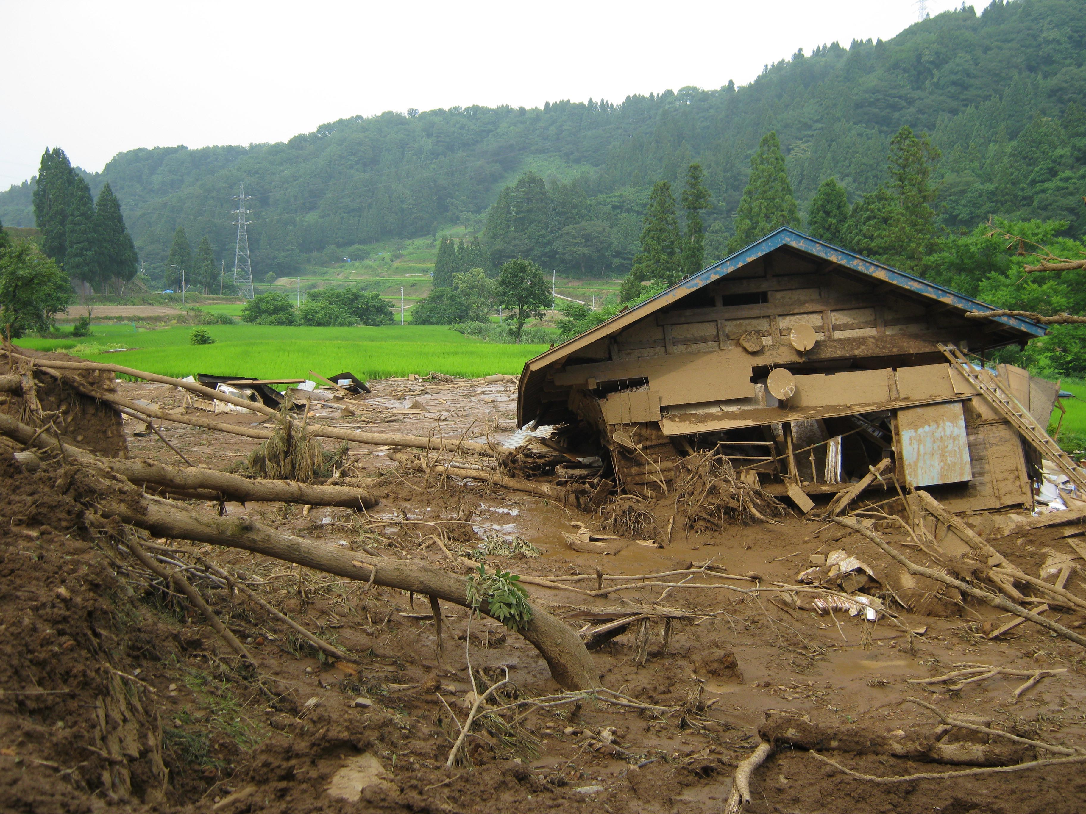 写真16 移動土砂末端部での住宅の倒壊.住宅は段丘上に位置しているが,地すべり地形からの流出土砂によって倒壊している.